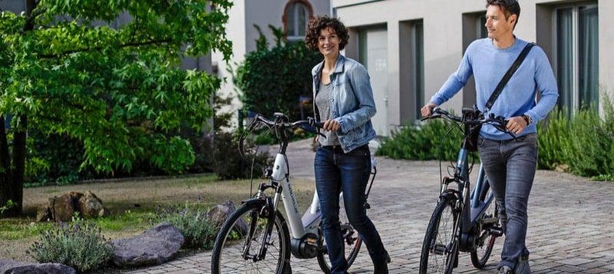 Zwei Personen schieben E-Bikes in urbaner Umgebung