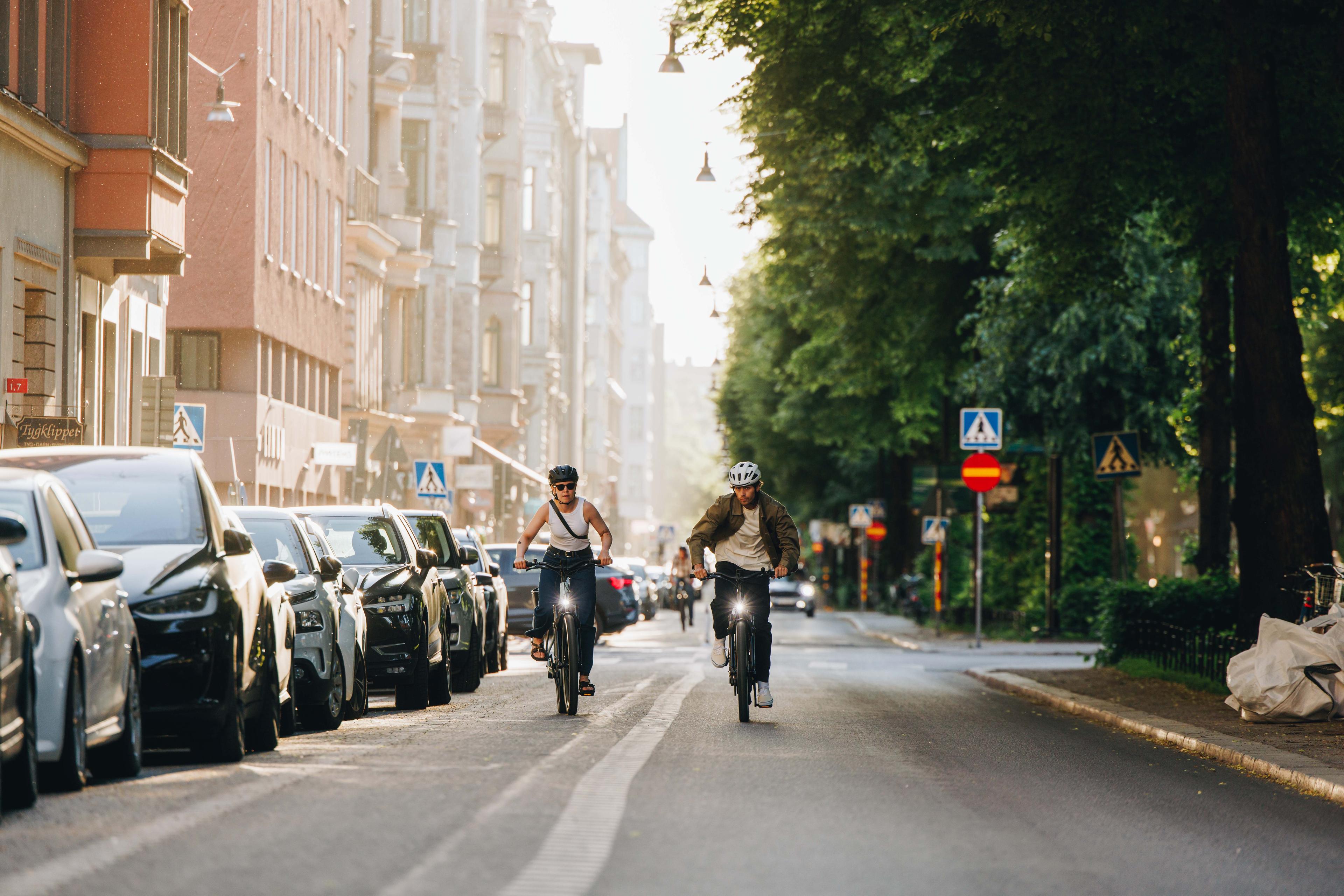 Zwei Personen fahren nebeneinander auf Fahrrädern durch eine städtische Umgebung.