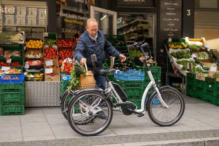 Mann mit E-Bike vor einem Obst- und Gemüseladen