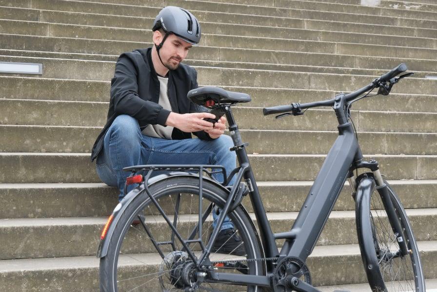 Mann mit Helm sitzt auf Treppe neben modernem E-Bike