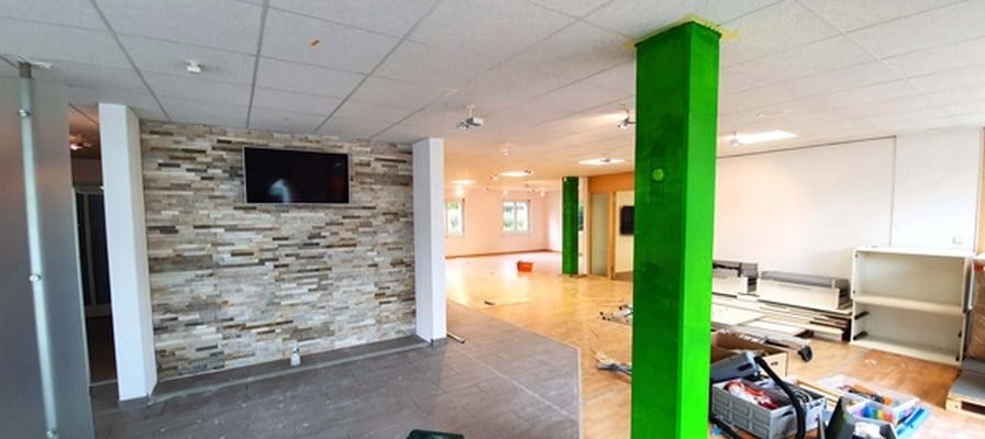 Innenraum eines renovierten Geschäfts mit grüner Säule und Steinwand