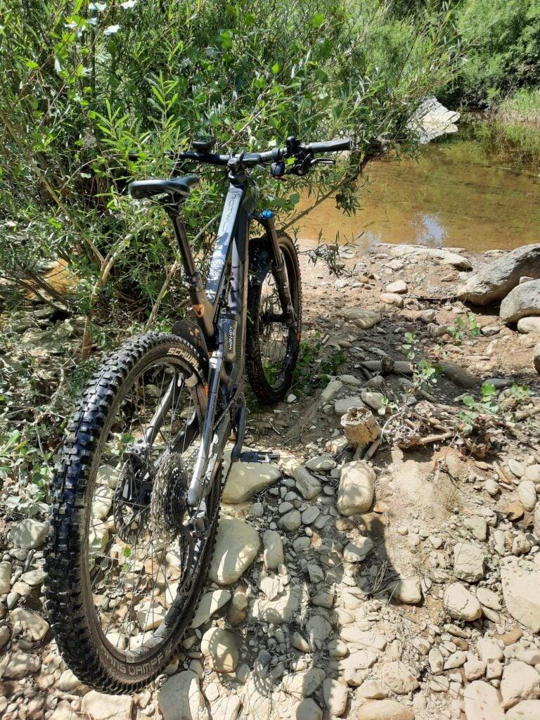 Mountainbike auf steinigem Flussufer im Grünen