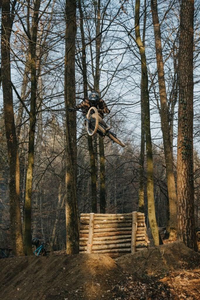 Mountainbiker springt über Rampe im Wald