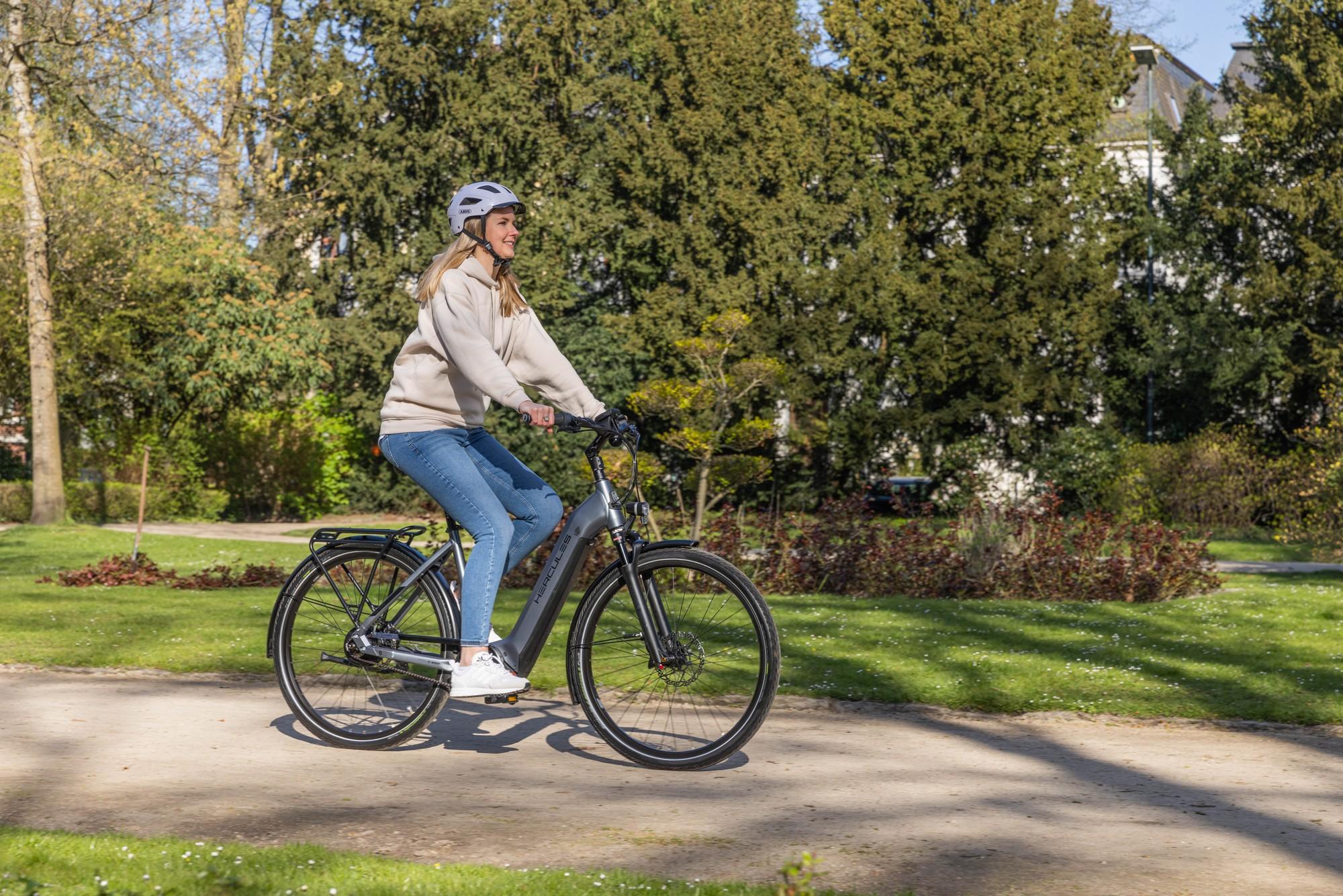 Eine Frau fährt auf einem Hercules Futura HD I auf einer Landstraße.