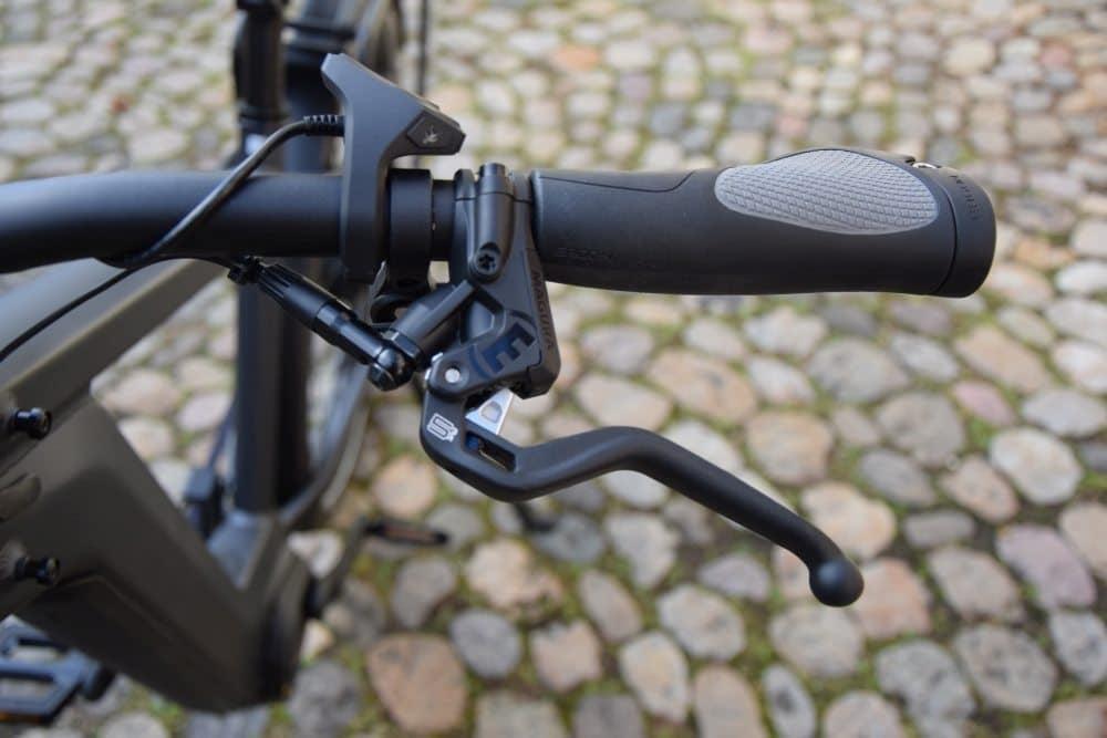 Nahaufnahme eines Fahrradlenkers mit Bremshebel und Griff auf Kopfsteinpflaster