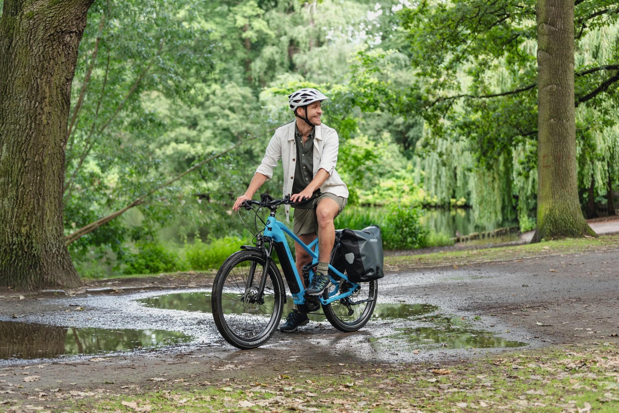 Das Bild zeigt einen Mann im Regen auf einem e-Bike mit einer Ortlieb Fahrradtasche