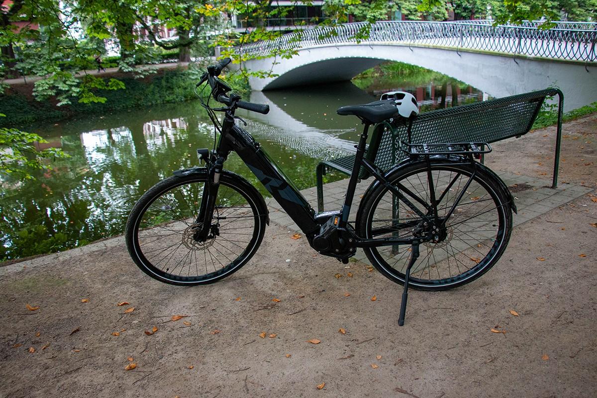 Eine Parkbank mit Helm, daneben das Testbike Raymon Cityray