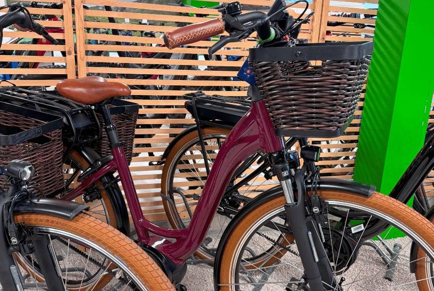 Lila E-Bike mit Korb und braunen Reifen in Fahrradständer