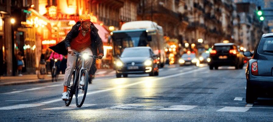 Mann fährt bei Nacht mit E-Bike durch belebte Stadtstraße