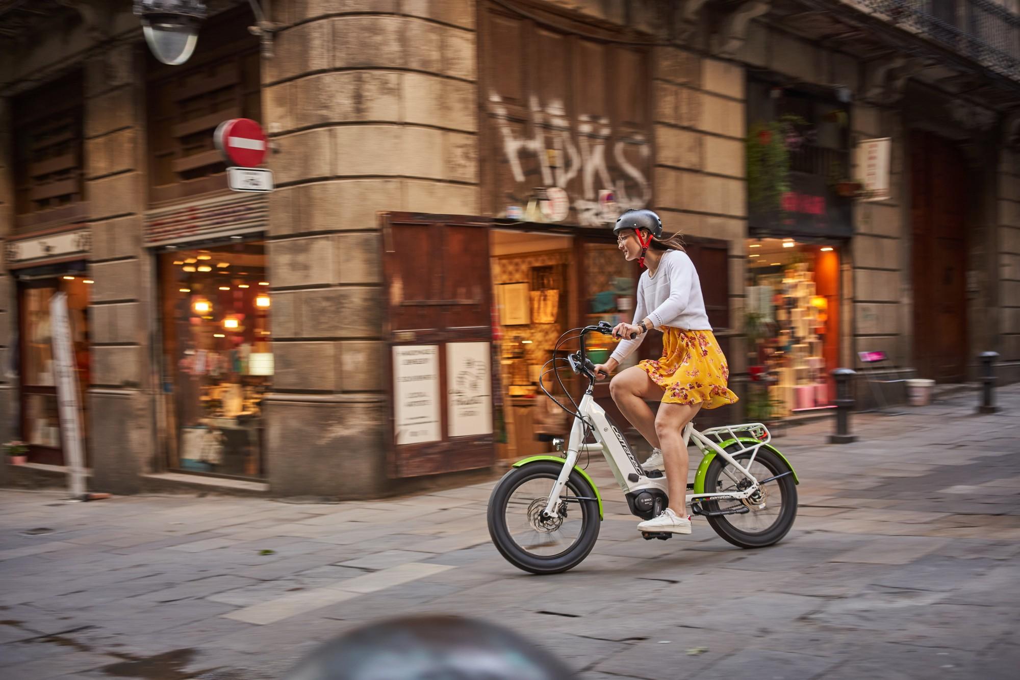 Das Bild zeigt eine Person, die auf einem Corratec LifeS E-Bike in einer urbanen Umgebung in Barcelona fährt. Das E