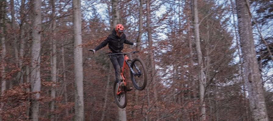 Mountainbiker springt mit Fahrrad durch herbstlichen Wald