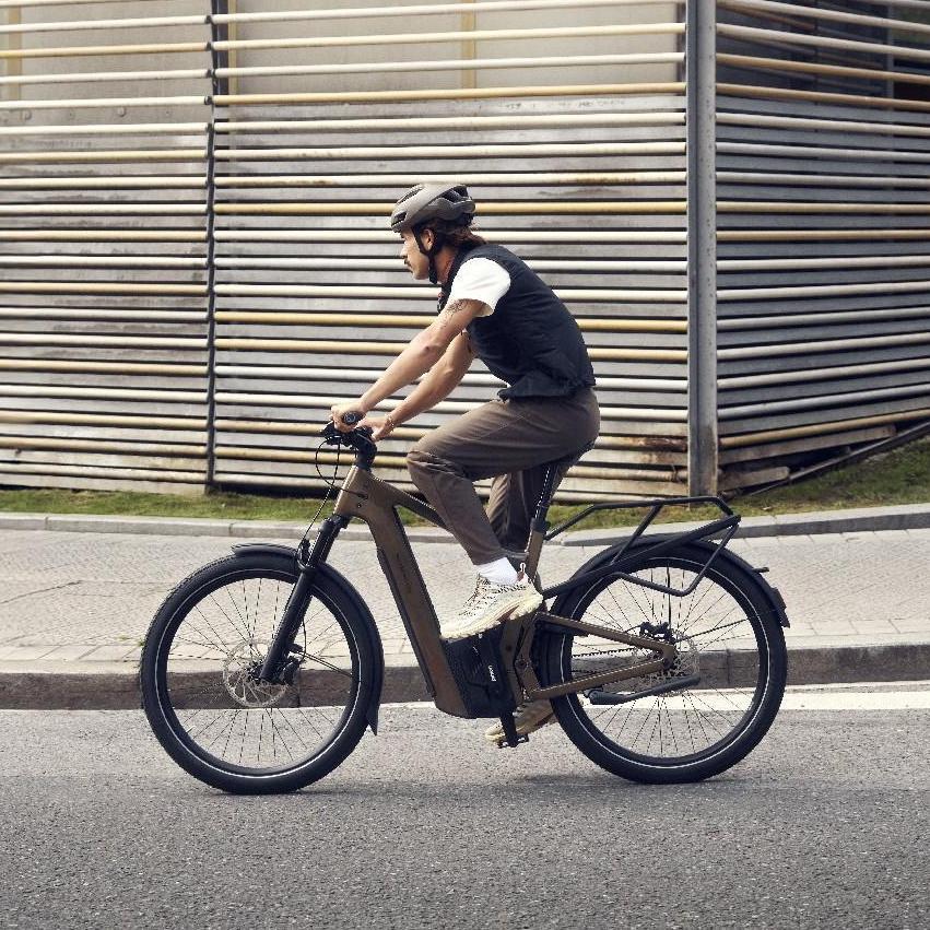 Eine Person auf einem Riese & Müller Delite e-Bike fährt an einer besonderen Wand entlang