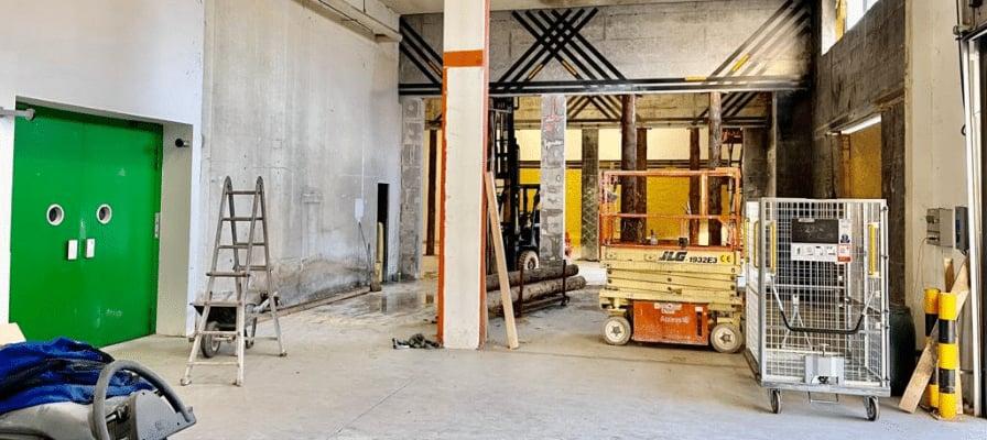 Industriehalle mit Hebebühne und Leiter in Bauumgebung