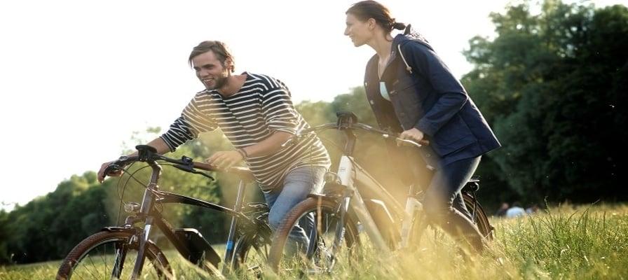 Zwei Personen auf E-Bikes bei sonnigem Ausflug durch die Natur