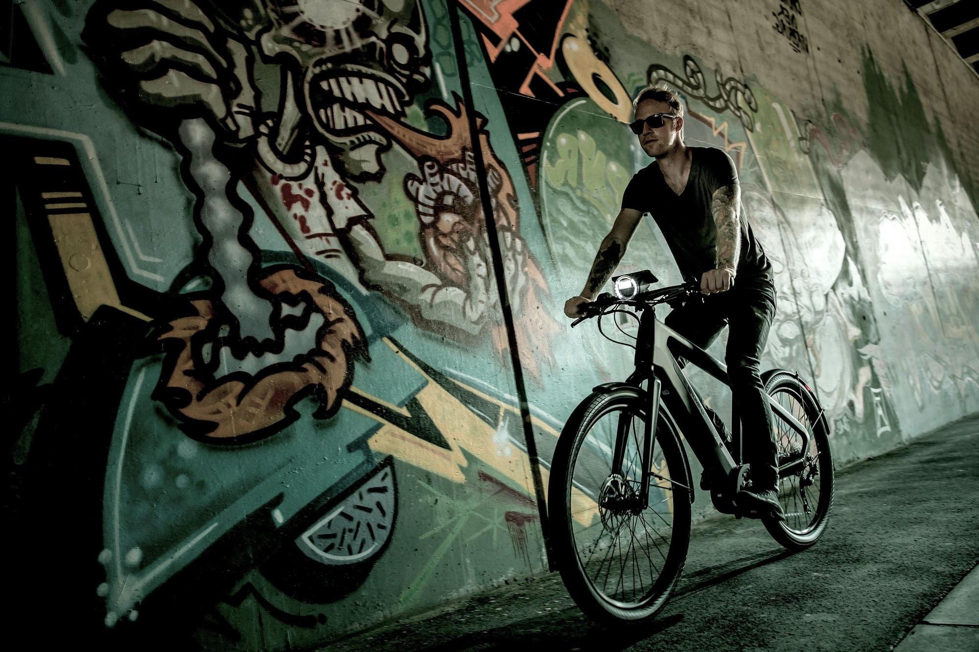 Ein Mann fährt auf dem Winora Radar e-Bike an Graffitis vorbei