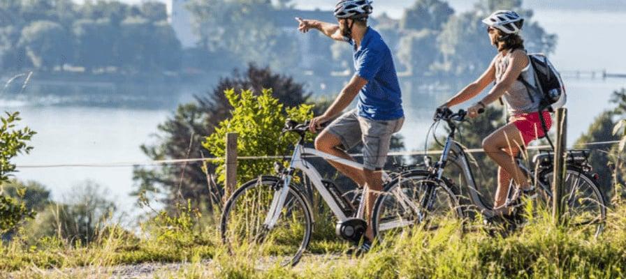 Zwei Personen fahren auf E-Bikes in der Natur mit Helmen