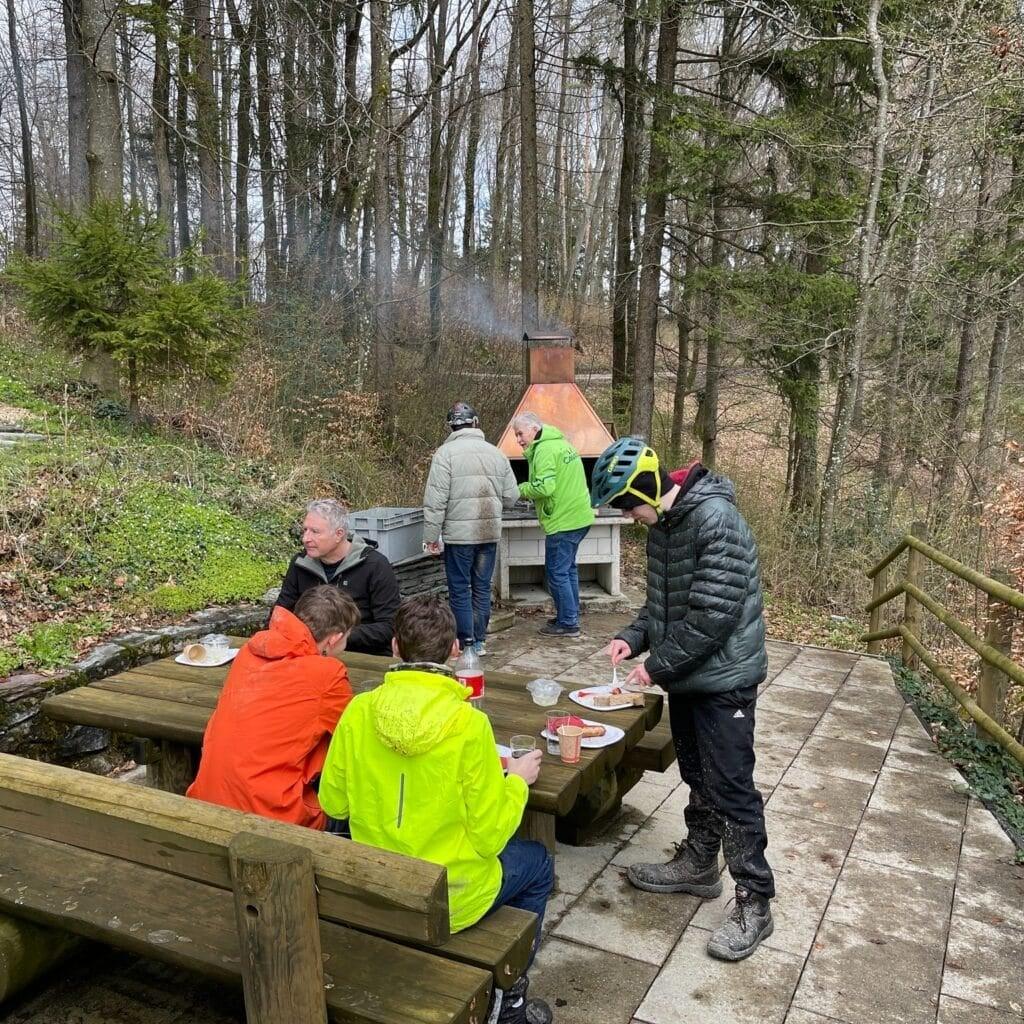 Gruppe beim Picknick im Wald an einem Grillplatz