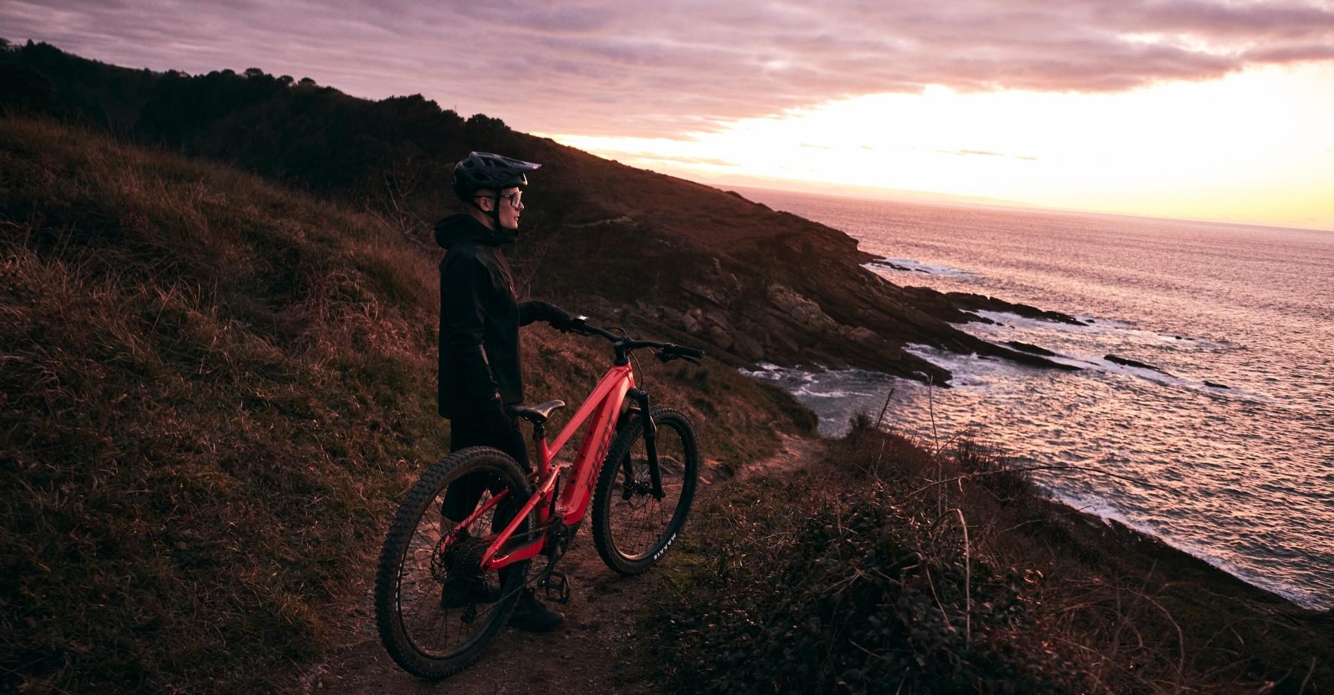 Eine Person hält das Giant Stance E+ und steht am Meer