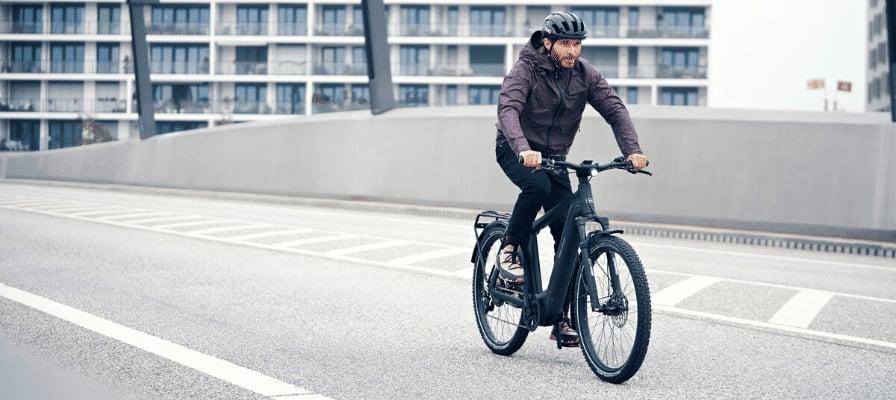 Mann fährt Riese & Müller Charger4 E-Bike auf einer Brücke