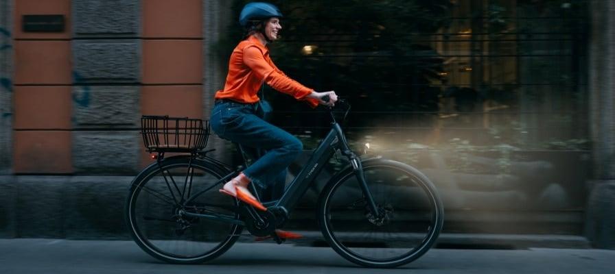Frau fährt Bianchi T-Tronik E-Bike durch Stadt bei Nacht