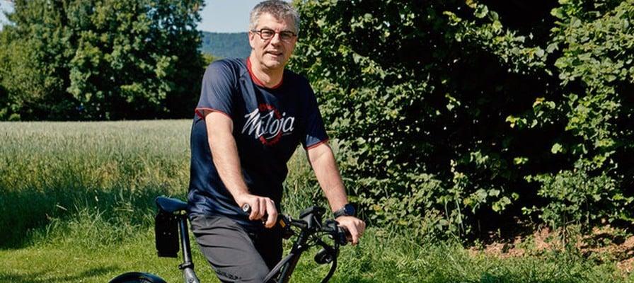 Mann auf einem Lasten-E-Bike vor einer grünen Landschaft