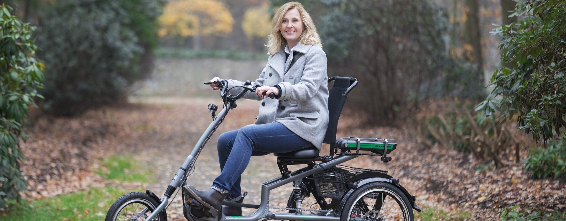 Frau auf einem Dreirad-E-Bike auf einem Waldweg