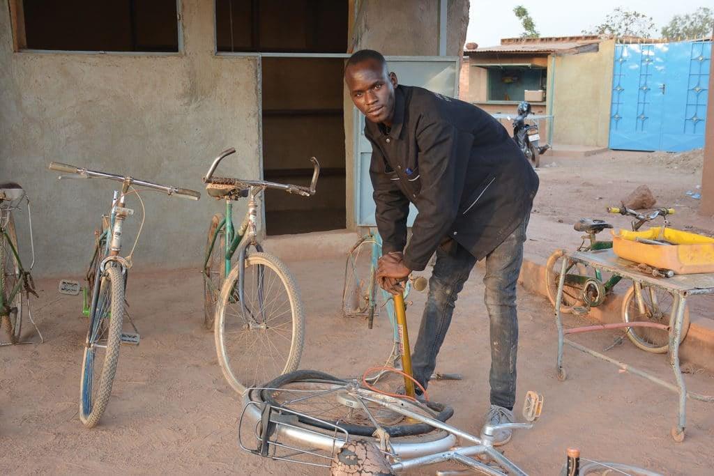 Mann repariert Fahrrad in Werkstatt im Freien