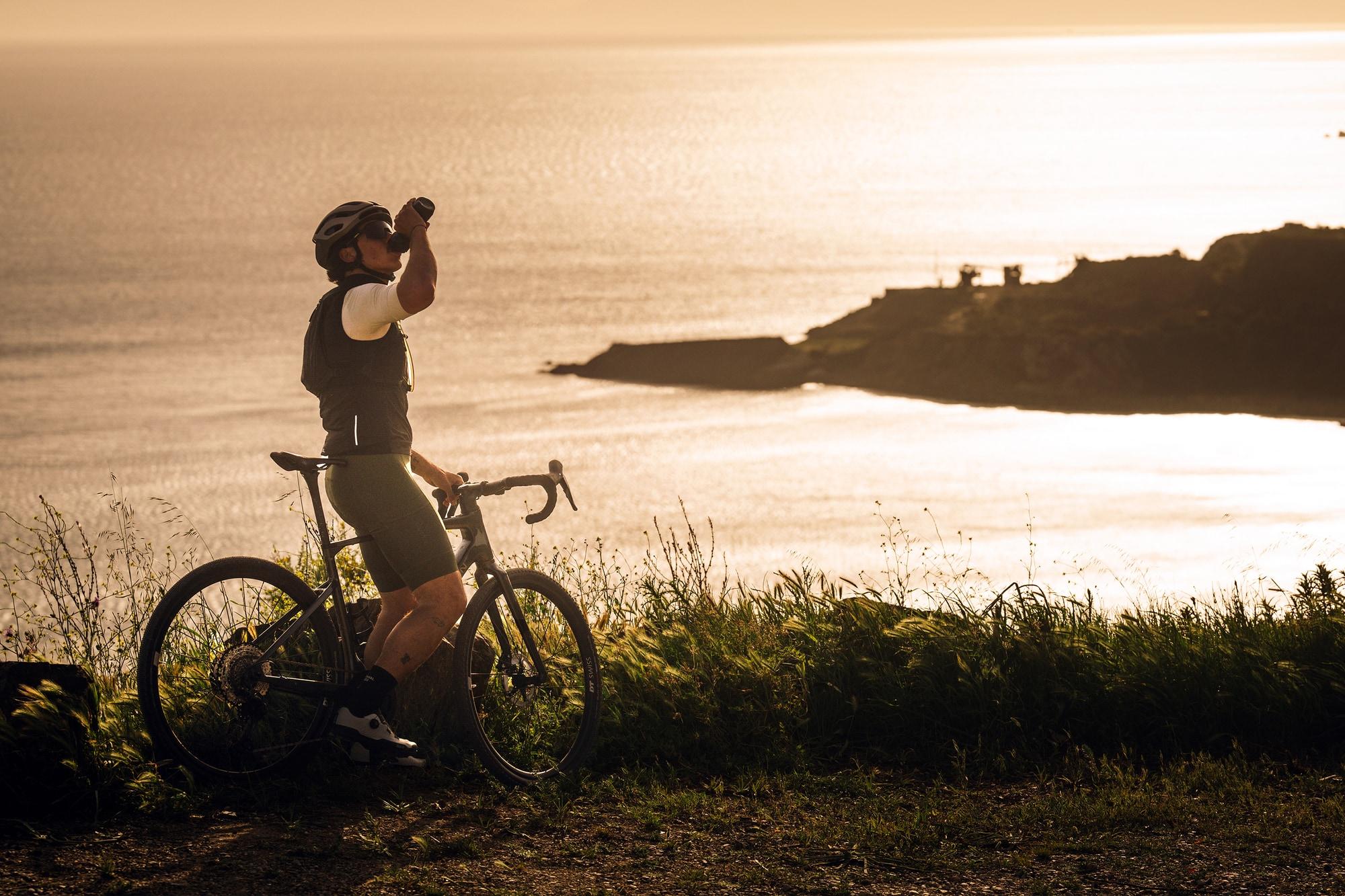 Fahrradfahrer steht mit seinem Grave-Bike am Meer, eine der komoot Routen von e-motion.