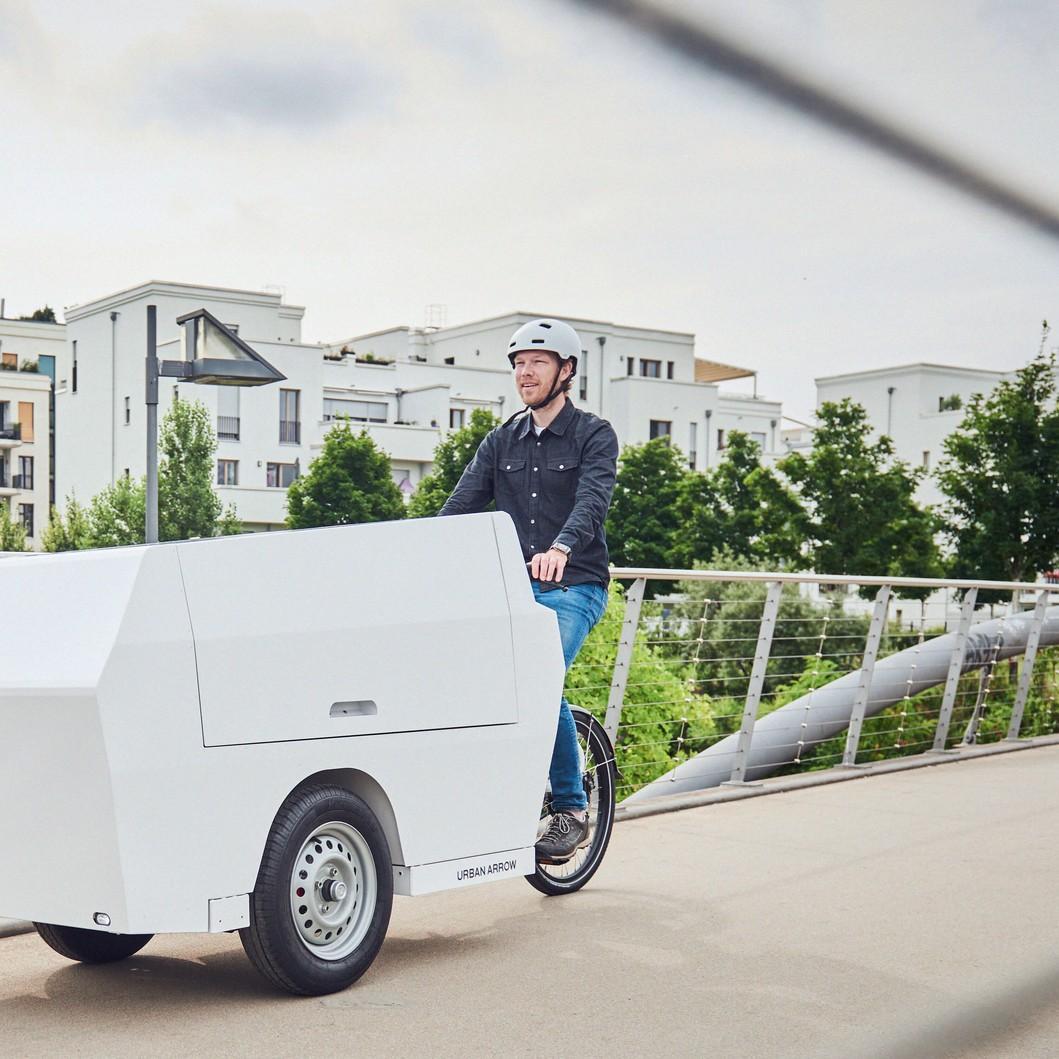 Mann fährt mit Urban Arrow Tender Lastenrad über eine Brücke