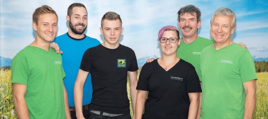 Gruppe von Menschen in bunter Kleidung vor Landschaftshintergrund