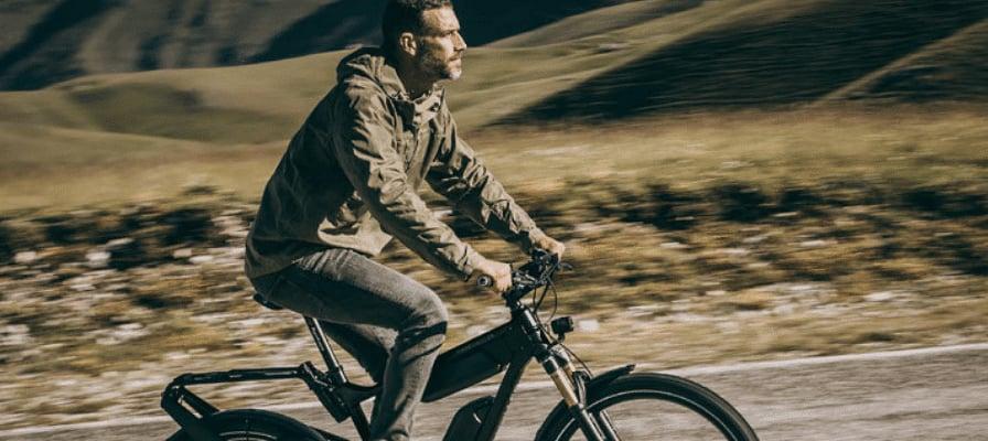 Mann fährt Riese & Müller E-Bike auf ländlicher Straße