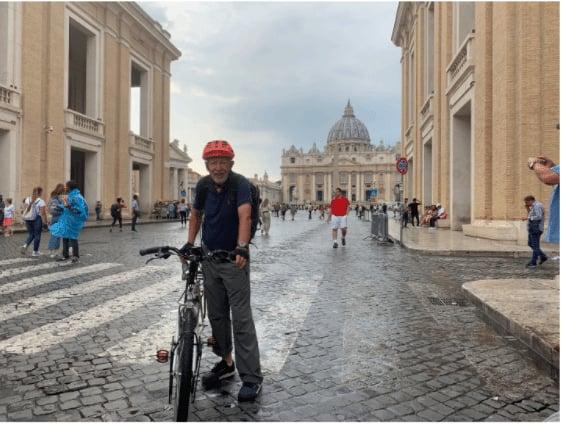 Mann mit Fahrrad auf Kopfsteinpflaster vor historischer Architektur