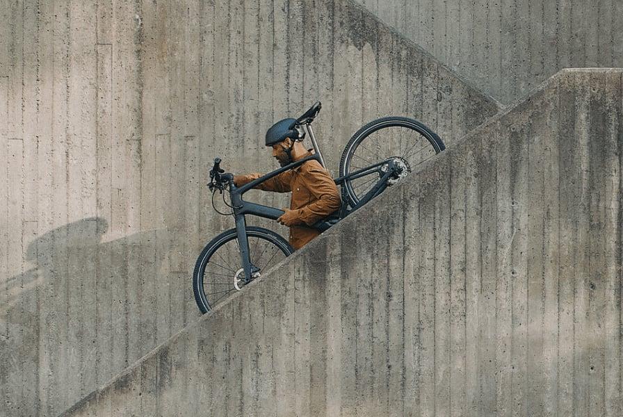 Mann trägt Specialized Vado SL E-Bike eine Betontreppe hinauf