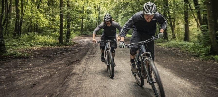 Zwei Mountainbiker fahren dynamisch auf Waldweg