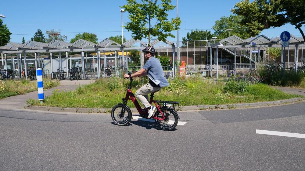Das Bild zeigt einen E-Bike-Fahrer, der auf einem roten E-Bike fährt.