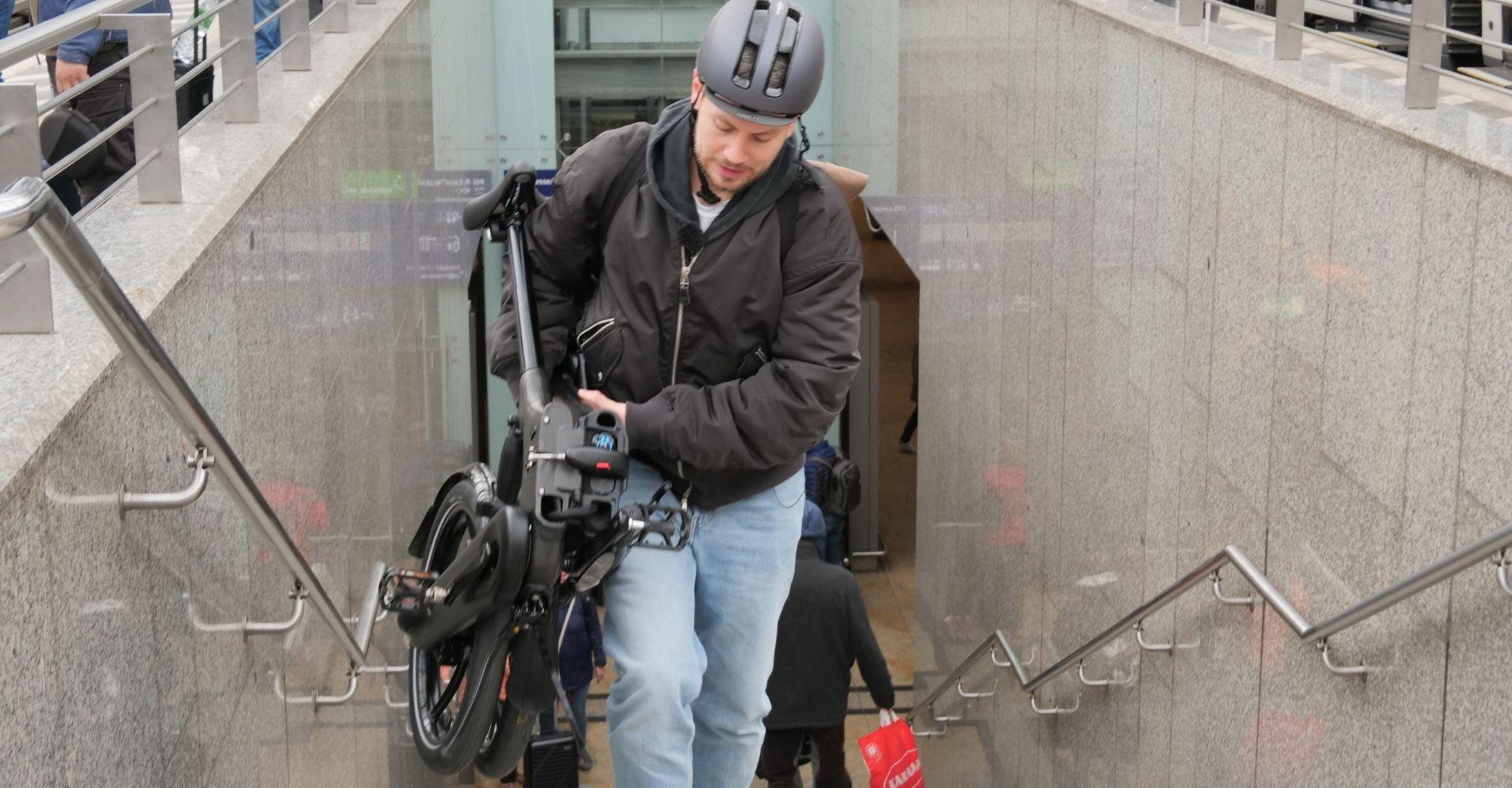 Mann trägt Brompton Klapprad die Treppen am Bahnhof hoch