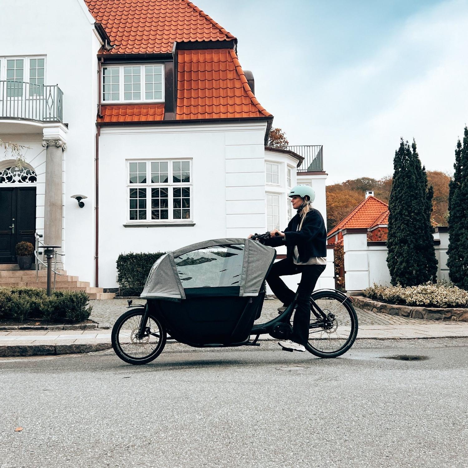 Eine Frau fährt mit dem neuen Winther W2 Lasten e-Bike durch ein Wohngebiet.