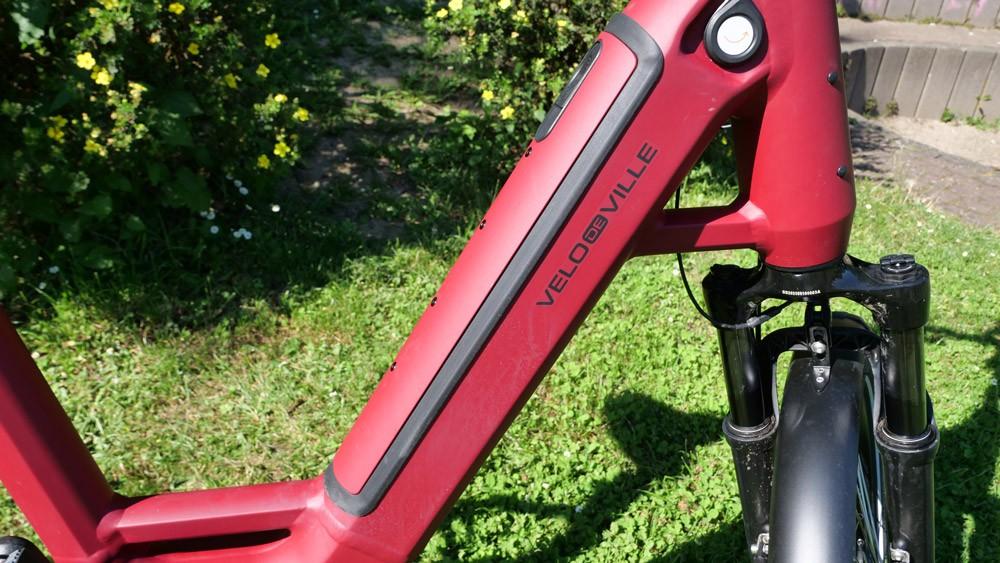 Das Bild zeigt einen E-Bike Rahmen des Herstellers Velo de Ville, der in einem auffälligen Rotton gestaltet ist
