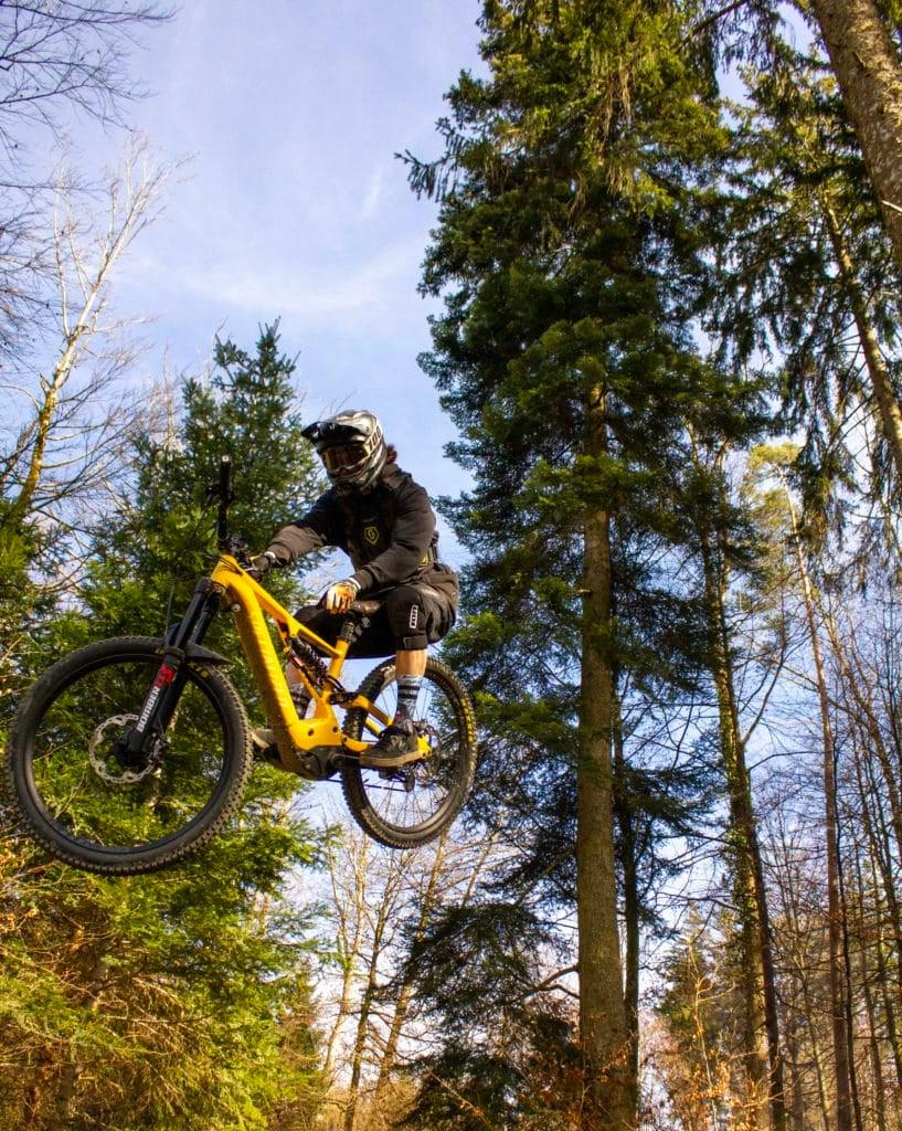 Mountainbiker springt mit gelbem E-Bike im Wald