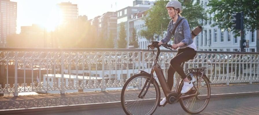 Frau auf Bosch E-Bike fährt über Brücke bei Sonnenuntergang