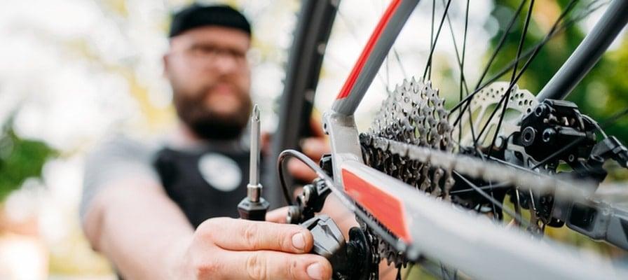 Mann justiert E-Bike-Kettenschaltung im Freien