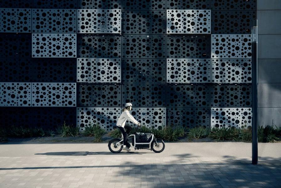 Person auf Riese & Müller E-Bike vor moderner Wand