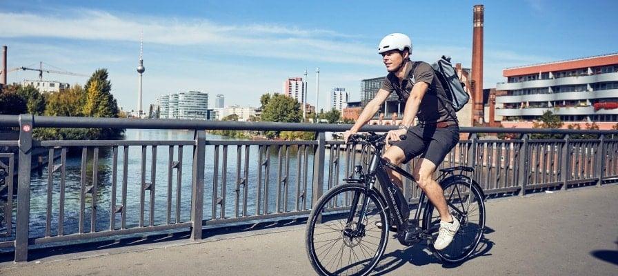 Mann auf Shimano Steps E-Bike fährt über Brücke in urbaner Umgebung