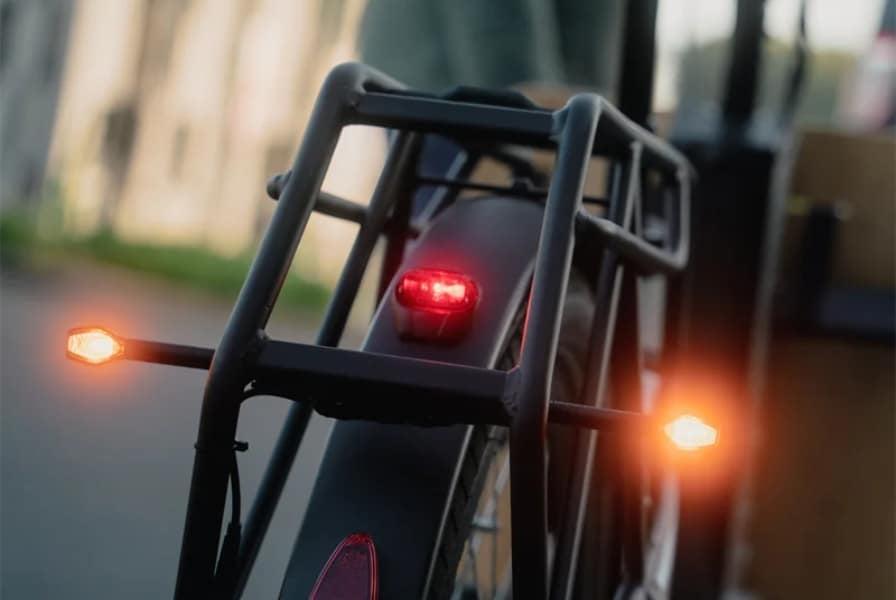 Rückansicht eines E-Bikes mit leuchtenden Rücklichtern und Gepäckträger