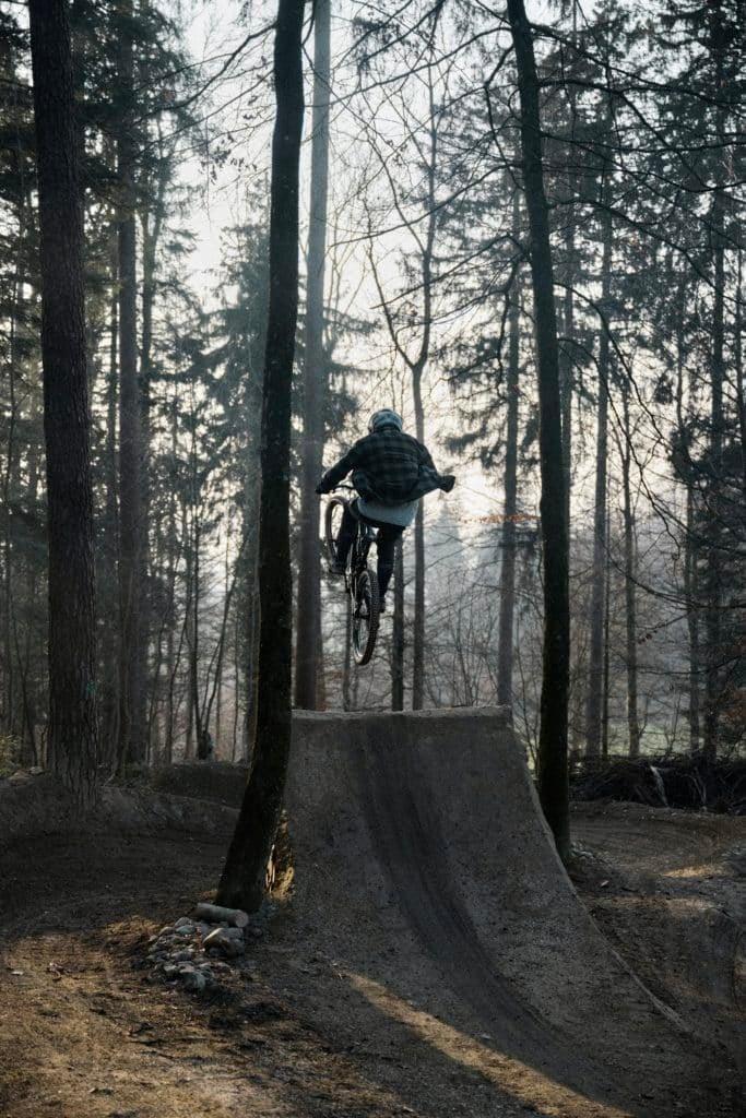 Mountainbiker springt über Rampe im Wald