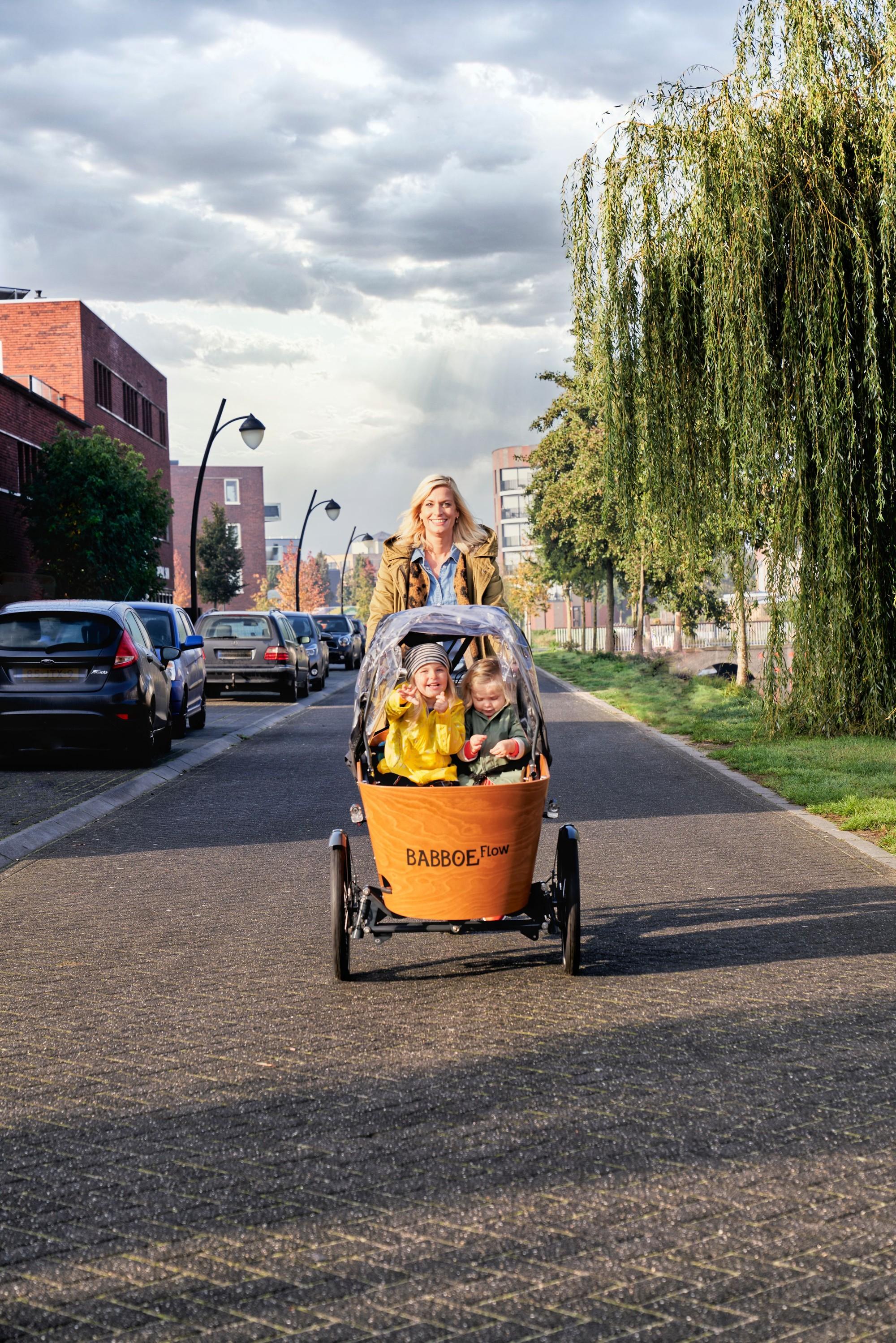 Eine Frau bringt ihr Kind auf dem Babboe Flow Lasten e-Bike zum Kindergarten.