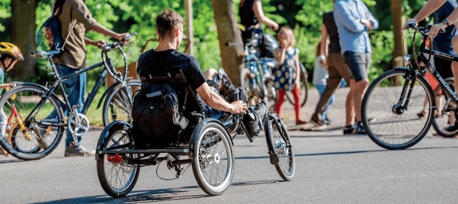Menschen mit Fahrrädern und Liegedreirad im Park