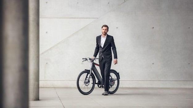 Mann im Anzug mit Stromer ST2 S E-Bike vor moderner Betonwand