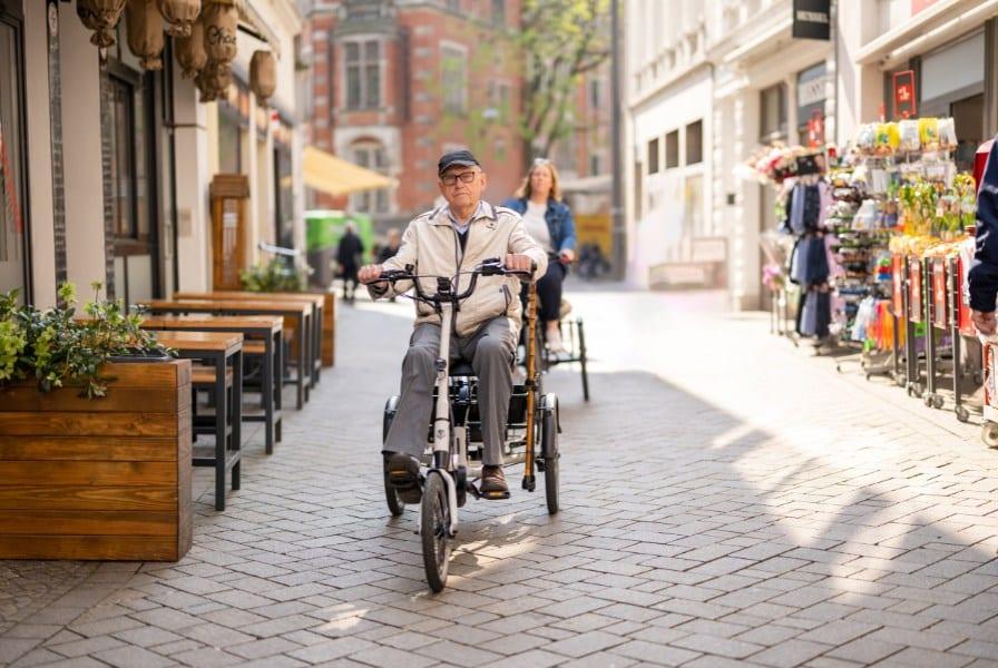 Zwei Personen fahren hintereinander auf Dreirädern durch die Stadt