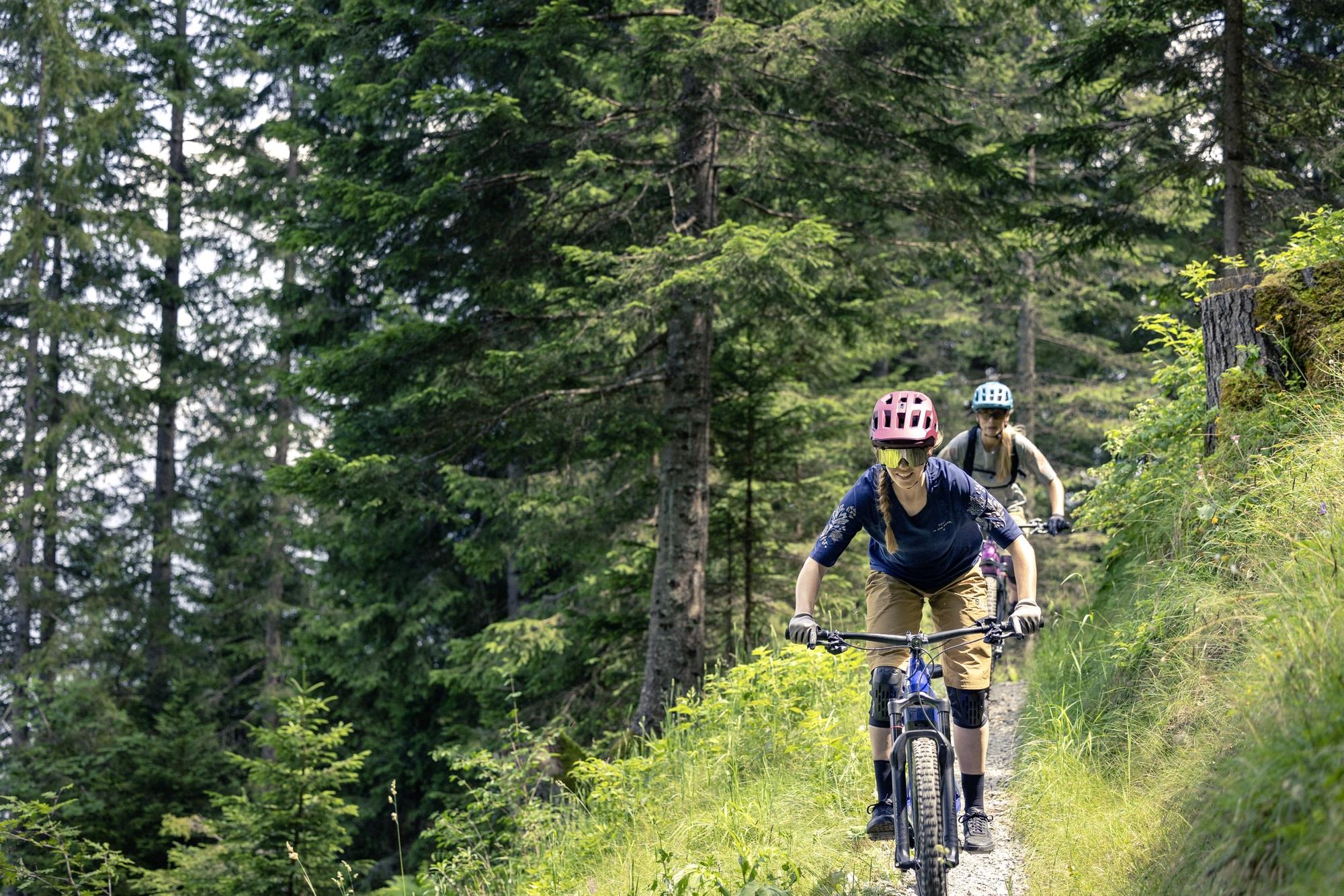 Zwei Personen fahren mit Bosch E-Bikes auf einem Waldpfad. Perfekt für abenteuerliche Touren in der Natur.